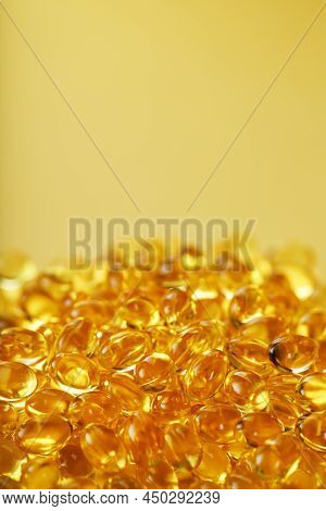 Heap Of Transparent Fish Oil Capsules On Yellow Background With Free Space