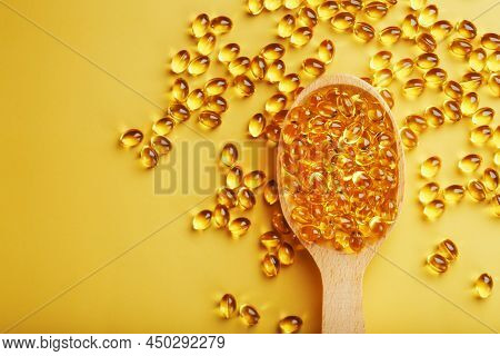 Vitamin D3 In A Wooden Spoon On A Bright Yellow Background