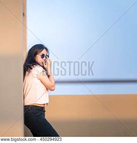 Cute Asian Woman Stands Up Against The Wall And Wears Blue Sunglasses At Rooftop Of The Building In 