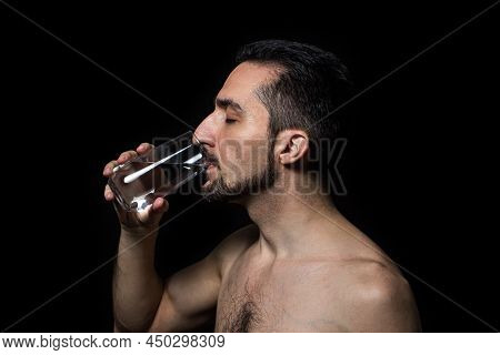 A Man Drinks Water On A Black Background. Pure Drinking Water. Thirst Quencher