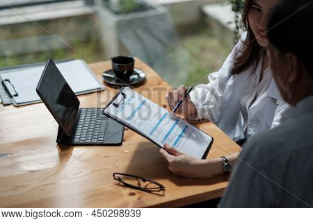 Female Health Insurance Broker Presenting His Insurance Benefits To Businessman Fill Out Insurance P