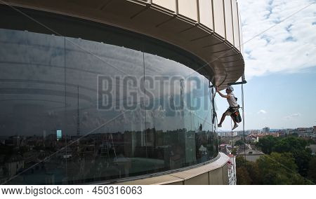 Industrial Mountaineering Worker Professional Window Washer Hanging On Climbing Rope And Cleaning Gl