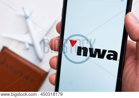 Nwa Airlines App On The Cell Phone Screen In Mans Hand With Plane, Boarding Pass And Passport On The