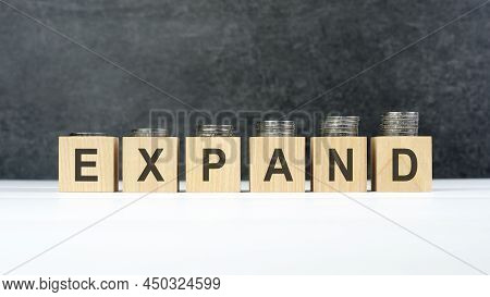 Expand Word, Text Written On Wooden Cubes On A Black Background With Coins On Cubes