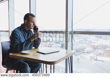 Happy Man With Coffee Calling Via Smartphone While Remote Working Laptop At Work Desk, Cheerful Free