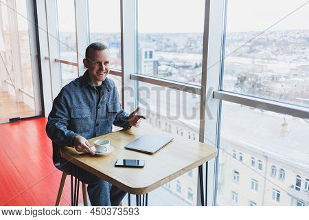Happy Man With Coffee Calling Via Smartphone While Remote Working Laptop At Work Desk, Cheerful Free