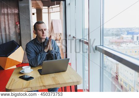 A Young Successful Businessman In A Suit Drinks Coffee And Works In A Cafe On Wireless Free Internet