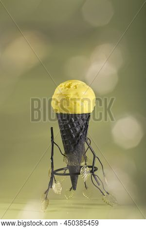 Homemade Yellow Fruit Flavored Ice Cream In A Dark Waffle Cone On A Light Background. Healthy Natura