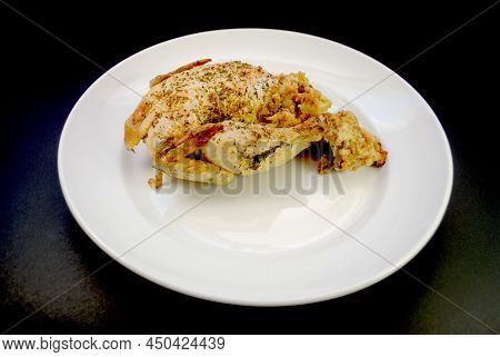 A Whole Stuffed Roasted Game Hen On A Platter Over A Black Background