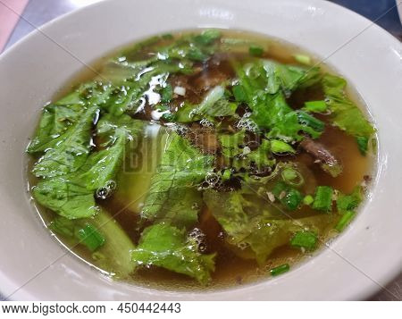 Clear Soup From Chicken Bone In A White Cup With Few Vetgetables. Focus At A Point