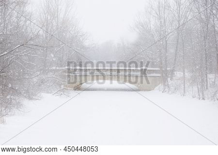 Stone foot bridge in park during blizzard