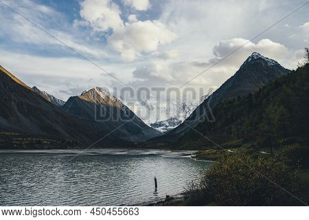 Awesome Alpine Landscape With Mountain Lake In Highland Valley And Snow-covered Mountain Wall And Ro
