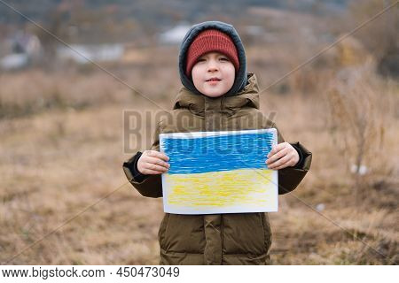 Ukrainian Crying Boy Holds A Painted Flag Of Ukraine. War Of Russia Against Ukraine. Ukrainian Cryin