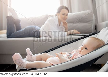 Closeup Baby In Automatic Carrycot, Businesswoman Working At Home Office Using Laptop Computer With 