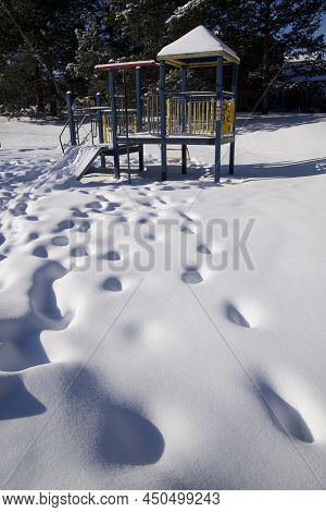 Panoramic Vertical Photo Of The Slide-kids Play Area Equipment Covered With Snow With Footprints In 