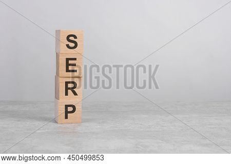 Wooden Cube On A Concrete Surface With Text Serp. Copy Space On Right For Design, Gray Background
