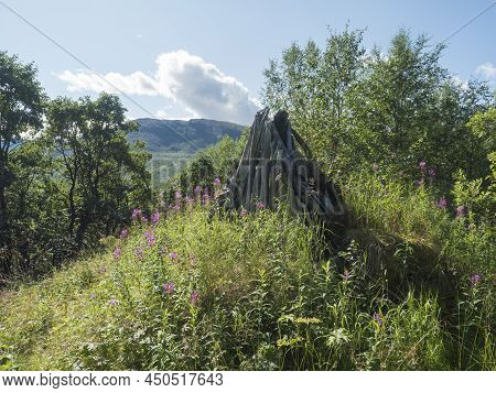 Abandoned Remains Of Mountains Shed Or Hut. A Pile Of Gray Wooden Logs Of Old Ruined Tourist Shelter