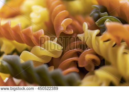 Three Colors Pasta Made From Durum Wheat. Pasta Fusilli Tricolor Background. Abstract Texture Of Col