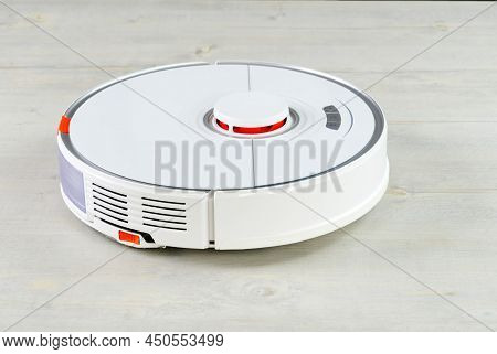 Robot Vacuum Cleaner On The Wooden Floor Cleaning The Room. Smart Cleaning And Washing Technology. A