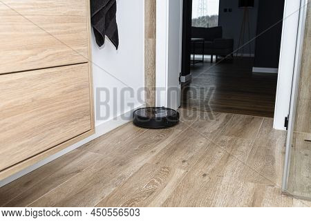 A Modern Robotic Vacuum Cleaner Cleans The Ceramic Tiles In The Bathroom Next To The Wall Mounted Ca