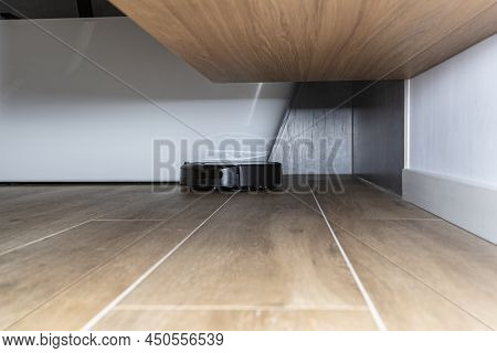 A Modern Robotic Vacuum Cleaner Cleans The Ceramic Tiles In The Bathroom Next To The Wall Mounted Ca