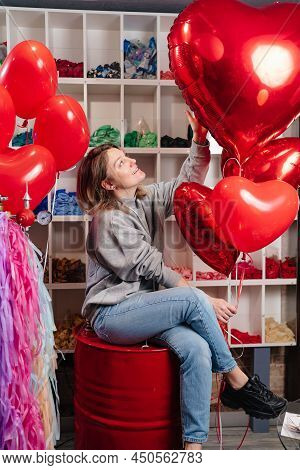 Woman On Red Decorative Barrel. With A Large Red Balloons In The Shape Of Heart.