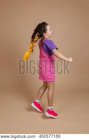 Cheerful Dancing Small Female Child With Two Yellow Kanekalon Pigtails Jumping Looking Away Smiling 