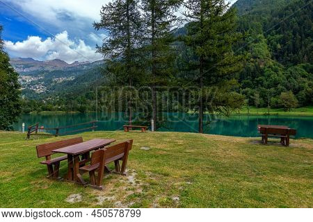 Picnic tables on the shore of the alpine Lake Maen in Aosta Valley region in Northern Italy.