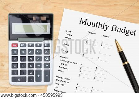 Doing Your Monthly Budget With A Calculator And Pen On A Wood Desk