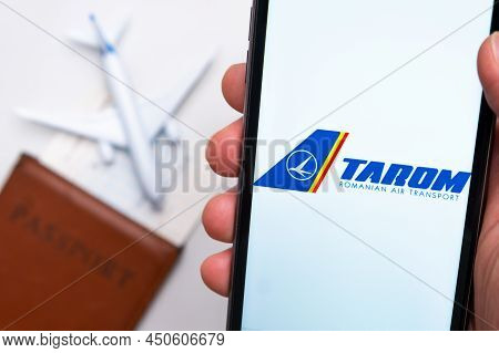 Tarom Romanian Air Transport Airlines App On The Cell Phone Screen In Mans Hand With Plane, Boarding