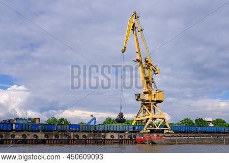 River Port Crane With Clamshell Or Griper Loading Coal To River Drag Boats Or Barges Moored By Pier 