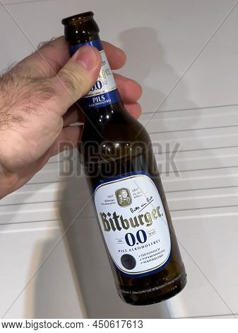 Paris, France - Jan 6, 2021: Pov Male Hand Holding Bottle Of Bitburger 0 Percent Beer - Kitchen Back