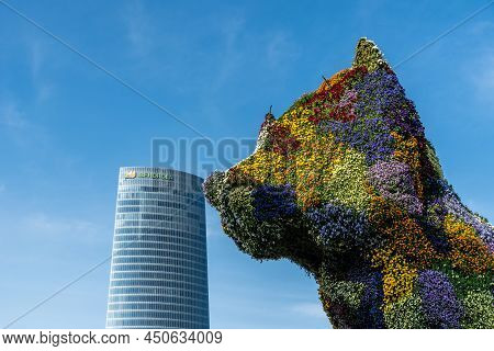 Bilbao, Spain - February 13, 2022: Puppy Sculpture Kissing Ibedrola Skyscraper. Puppy Is A A Behemot