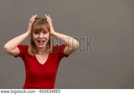 Young Woman Wearing Red Shirt Standing Over Gray Background With Hand On Head. Omg, Shoked, Surprise