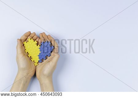 World Down Syndrome Day Background. Hands Holding Blue And Yellow Down Syndrome Awareness Day Heart 