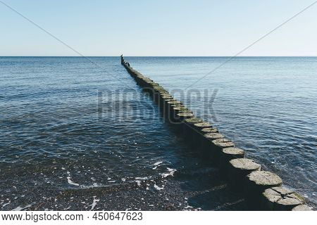 Wooden Breakwater In Calm Baltic Sea Against Blue Sky