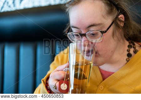 Indoor Portrait Of A 39 Year Old White Woman With The Down Syndrome Drinking Tea In A Bistro