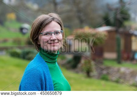 Close Up Portrait Of A Young White Woman With Glasses Wearing A Blue And Green Sweater With A Green 