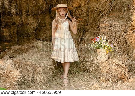 Blonde Teenage Girl Posing In Hayloft With Basket Of Wildflowers