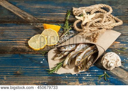 Sun-dried Smelt In A Paper Package. Salted Fish With Marine Decor. Lemon, Fresh Rosemary, Sea Rope