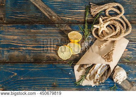 Sun-dried Smelt In A Paper Package. Salted Fish With Marine Decor. Lemon, Fresh Rosemary, Sea Rope