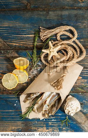 Sun-dried Smelt In A Paper Package. Salted Fish With Marine Decor. Lemon, Fresh Rosemary, Sea Rope