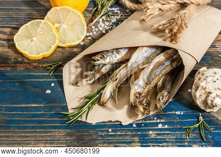 Sun-dried Smelt In A Paper Package. Salted Fish With Marine Decor. Lemon, Fresh Rosemary, Sea Rope
