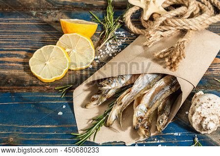 Sun-dried Smelt In A Paper Package. Salted Fish With Marine Decor. Lemon, Fresh Rosemary, Sea Rope