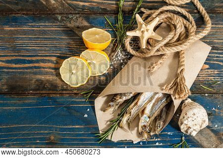 Sun-dried Smelt In A Paper Package. Salted Fish With Marine Decor. Lemon, Fresh Rosemary, Sea Rope