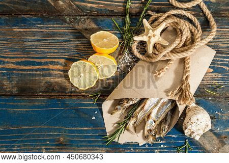 Sun-dried Smelt In A Paper Package. Salted Fish With Marine Decor. Lemon, Fresh Rosemary, Sea Rope