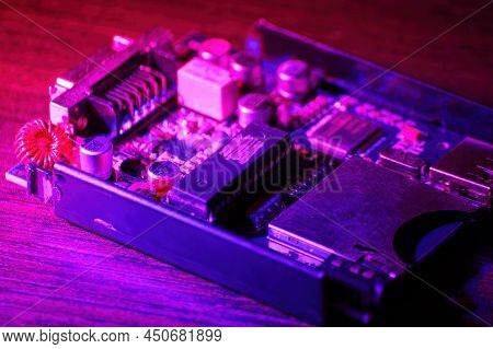 Small Pcb And Microcircuit Computer On The Table In The Purple Neon Lights. Abstract Technologies An