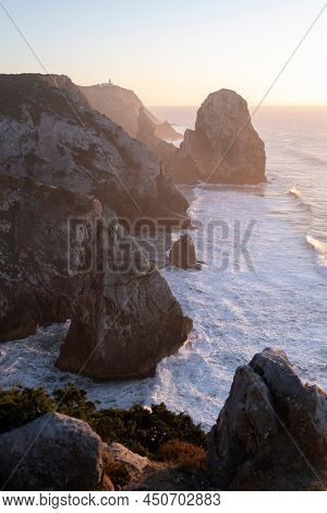 View of the cliffs and surf in the Atlantic Ocean at sunset, Miradouro da Praia do Caneiro, Portugal. 