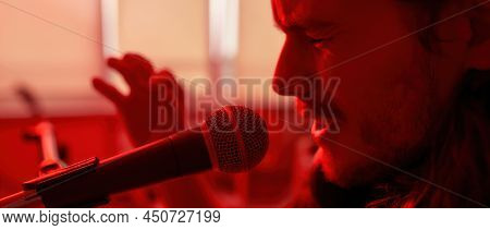 Partial Image Of Emotional Male Singer Sing Song In Microphone At Blurred Red Home. Domestic Hobby, 