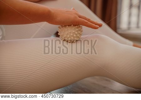 Athletic Slim Caucasian Woman Doing Thigh Self-massage With A Massage Ball Indoors. Self-isolating M